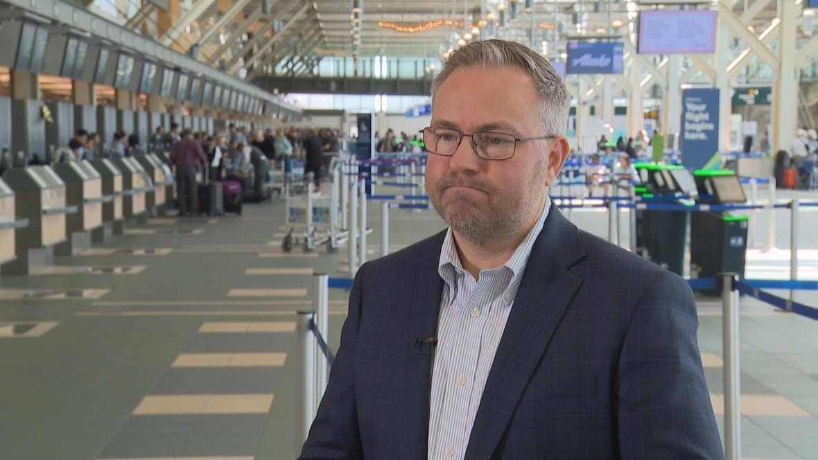 A man wearing a suit looks pensive in an airport.