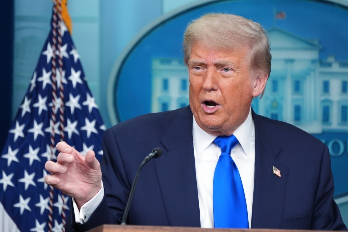 A man speaks at a podium in front of a U.S. flag.