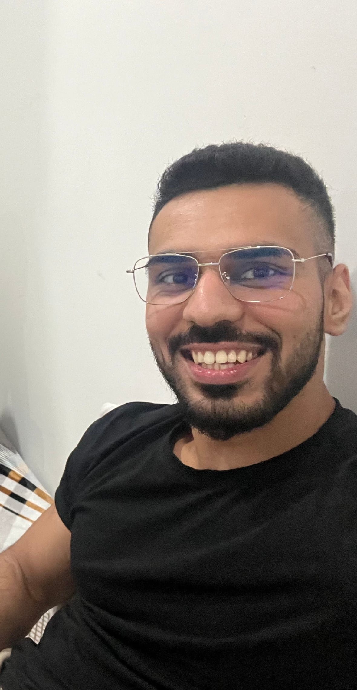 A man smiling with a beard wearing a black t-shirt.