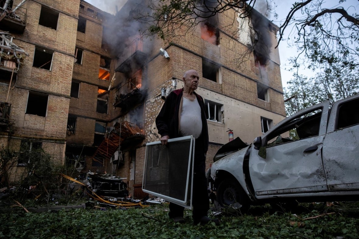 A resident carries window screens outside a damaged apartment building that is on fire after a Russian drone strike, amid Russia's attack on Ukraine, in Kyiv, Ukraine June 17, 2025.