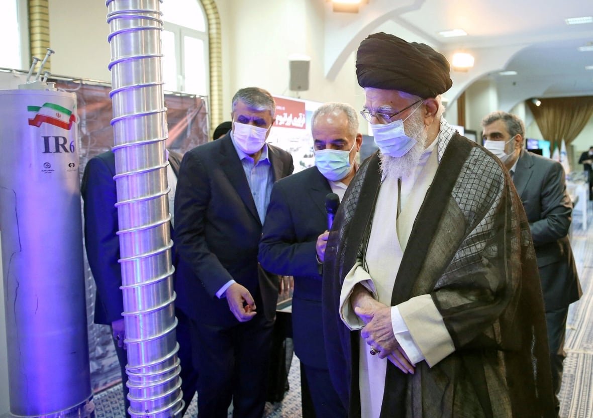 Four men wearing medical masks look at science equipment.