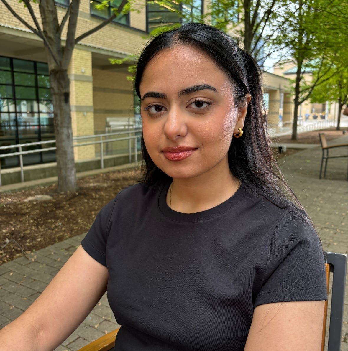 Wafa from the chest up with a building and trees in the background.