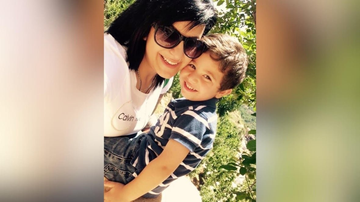 A woman in sunglasses and a little boy smile at the camera.