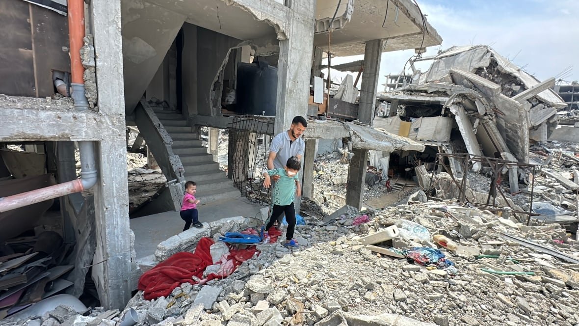 a man carries his son over rubble