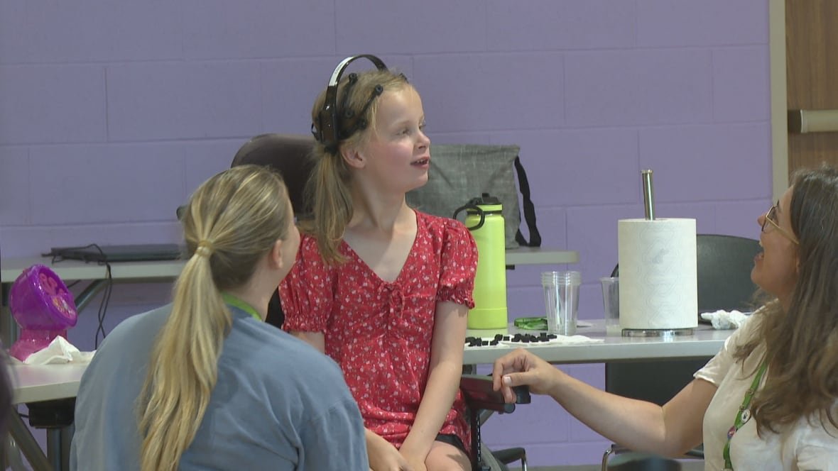 A girl wearing a headset in a wheelchair. 