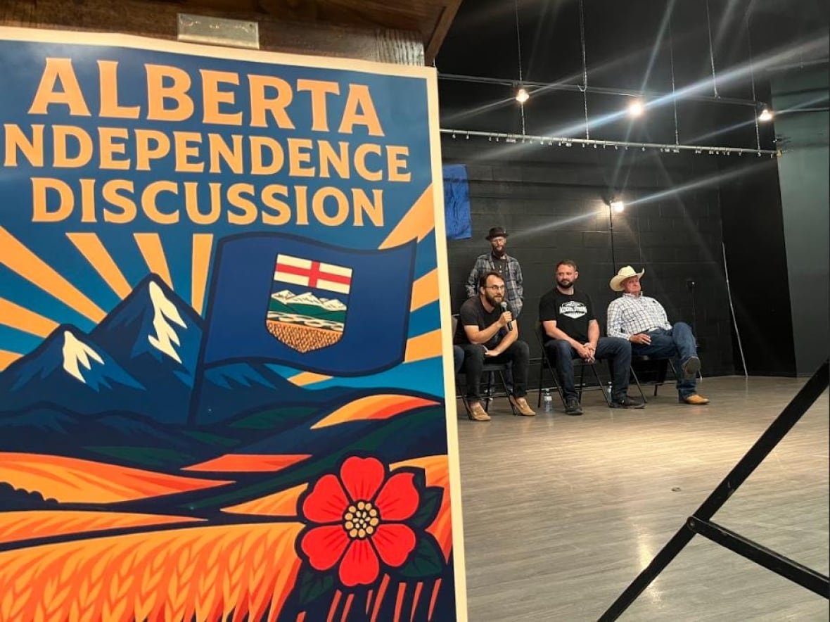 a big sign for Alberta independence in foreground, seated speakers in background