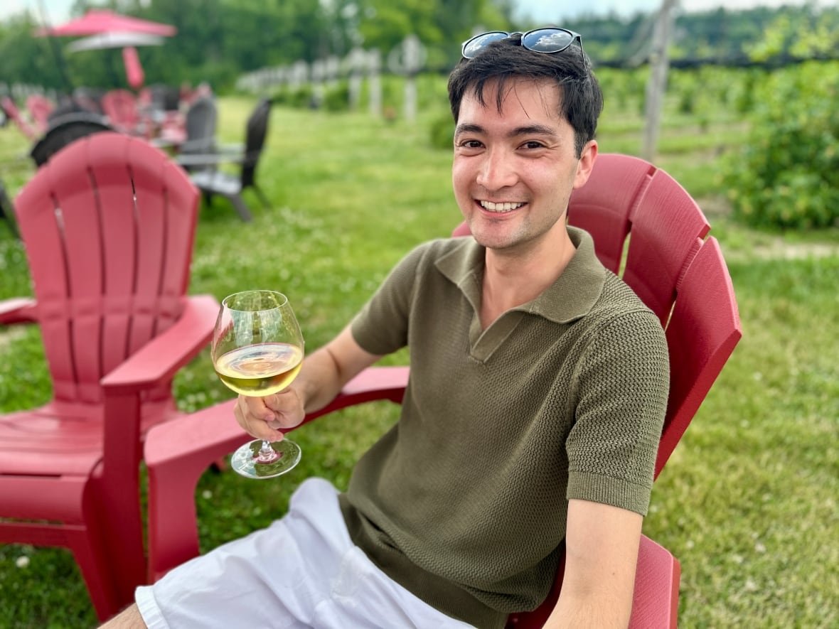 man in green shirt in red chair with wine glass