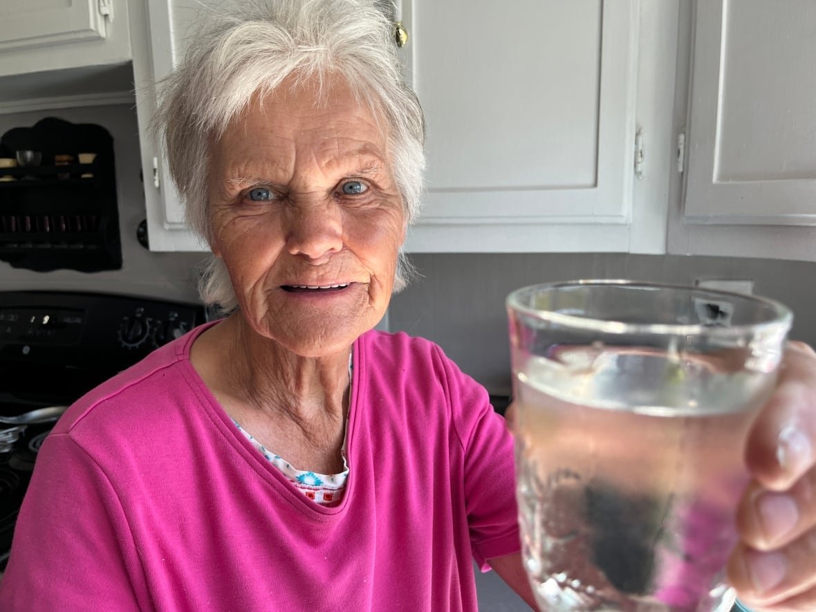 a woman holds up a glass of water