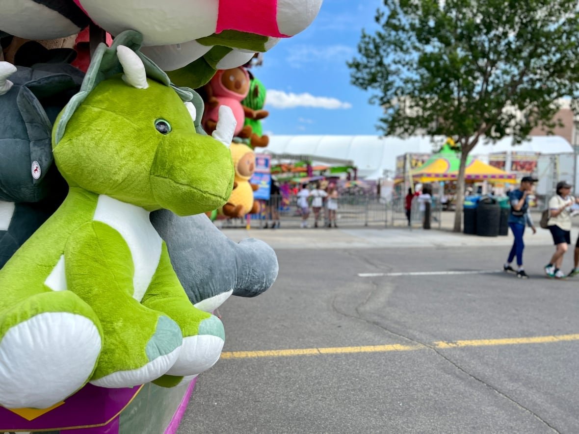 A green dinosaur stuffed animal is shown at the midway.