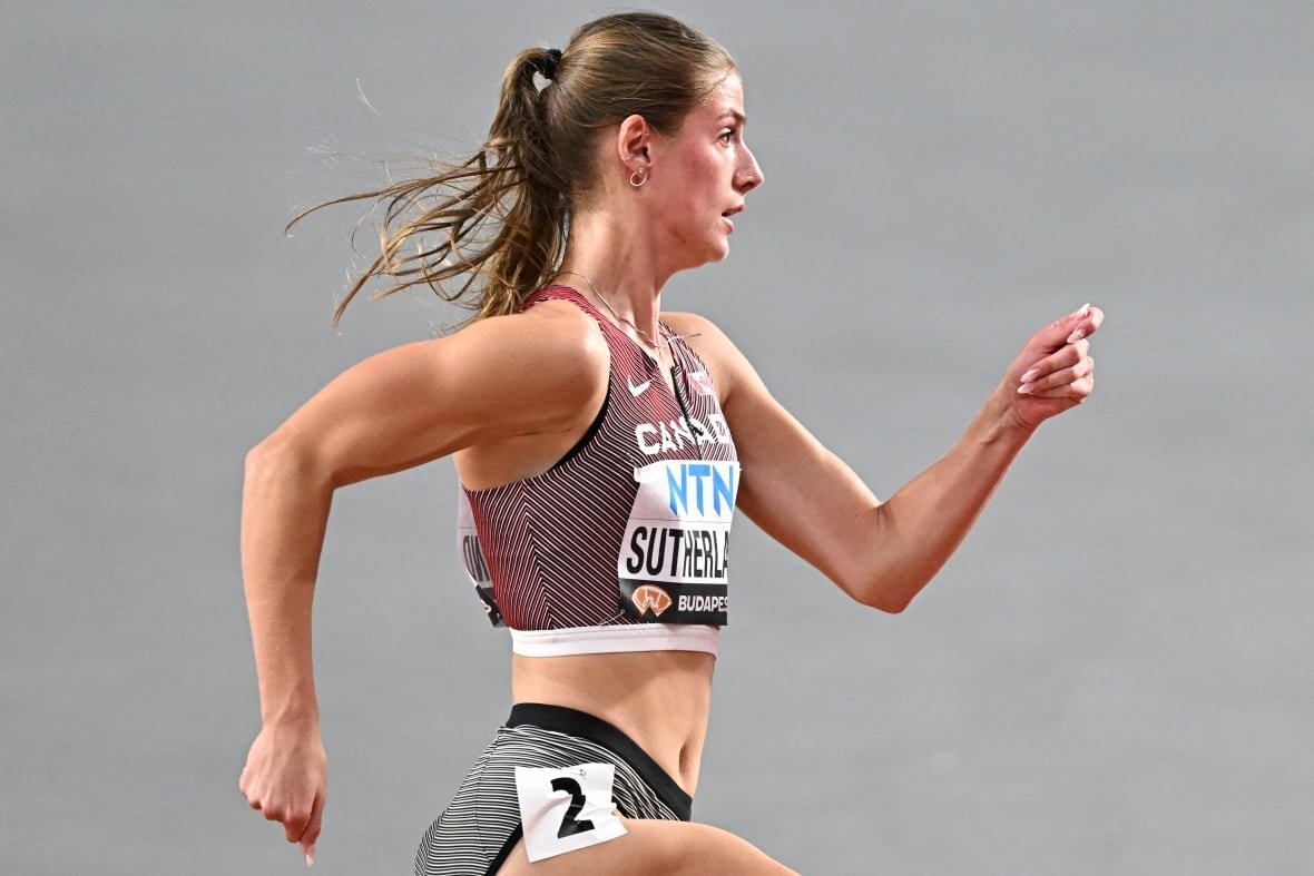 A women's track athlete is shown in profile while she runs.