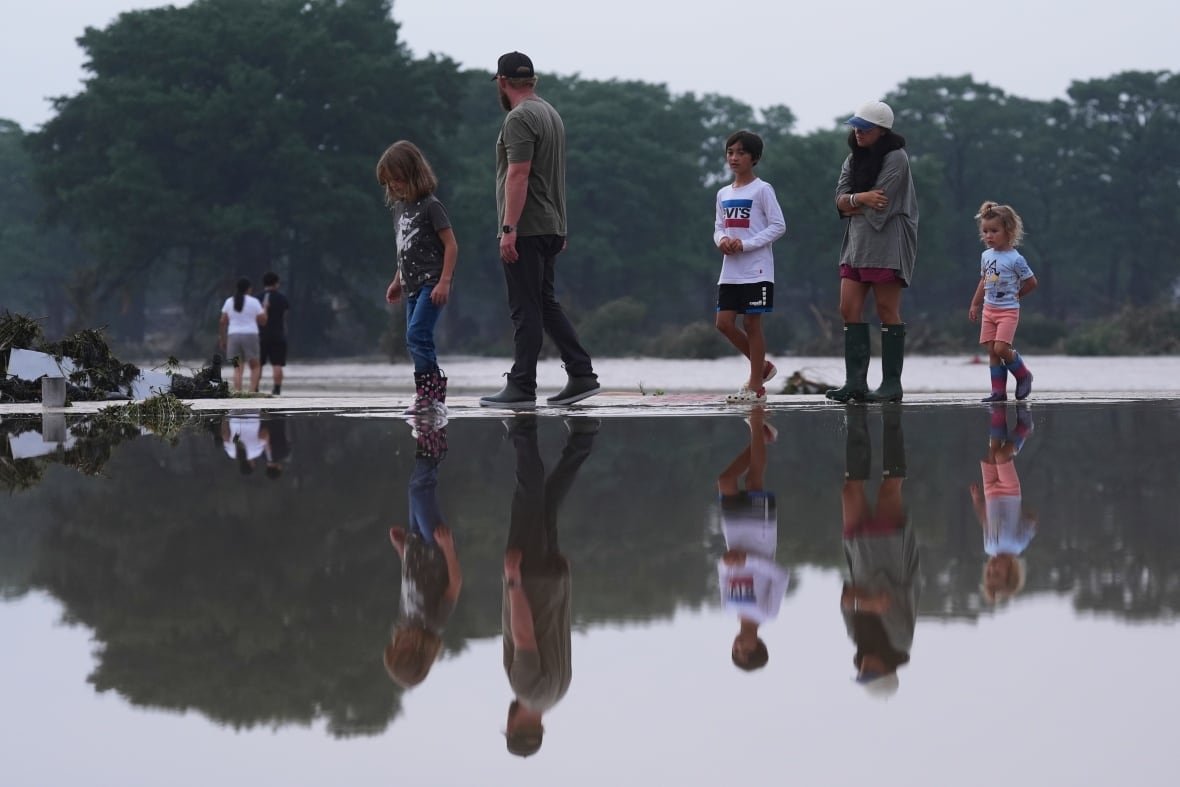 Onlookers survey damage along the Guadalupe River after a flash flood.