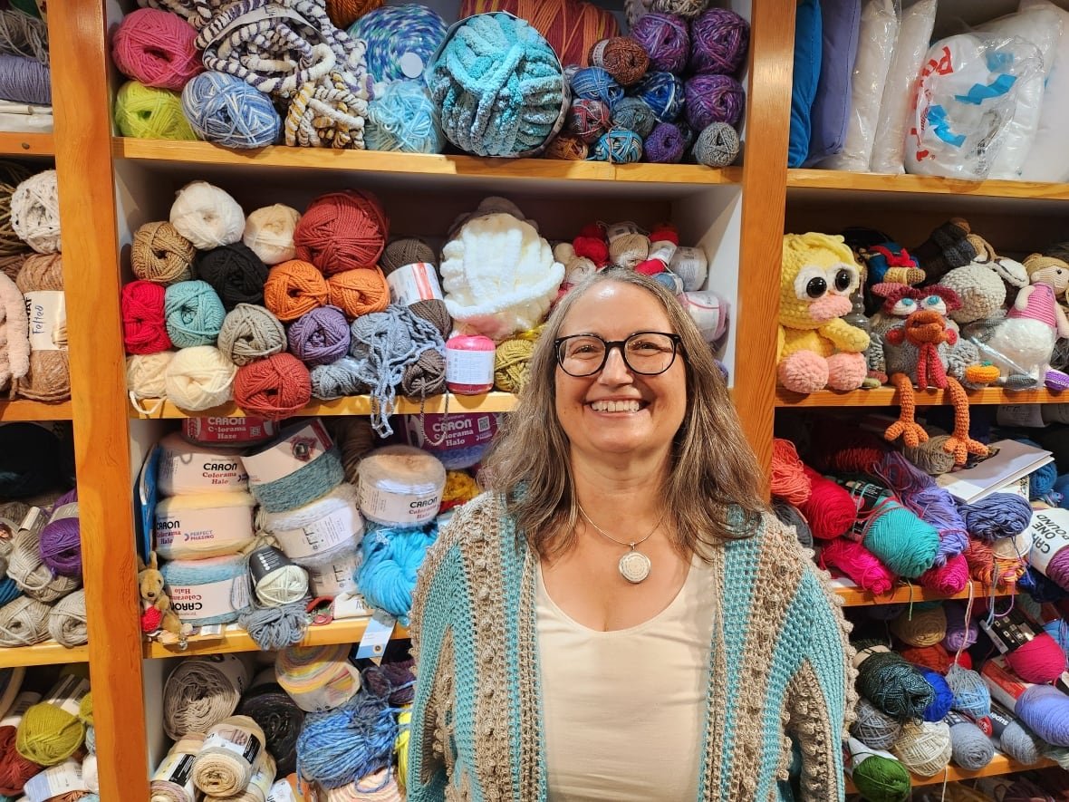 A woman in a turquoise cardigan smiles at the camera.