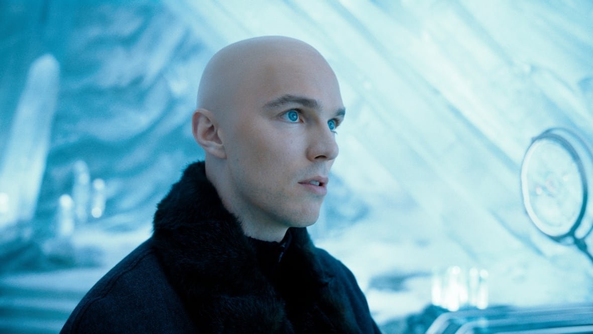 A bald man stands in a cave of ice