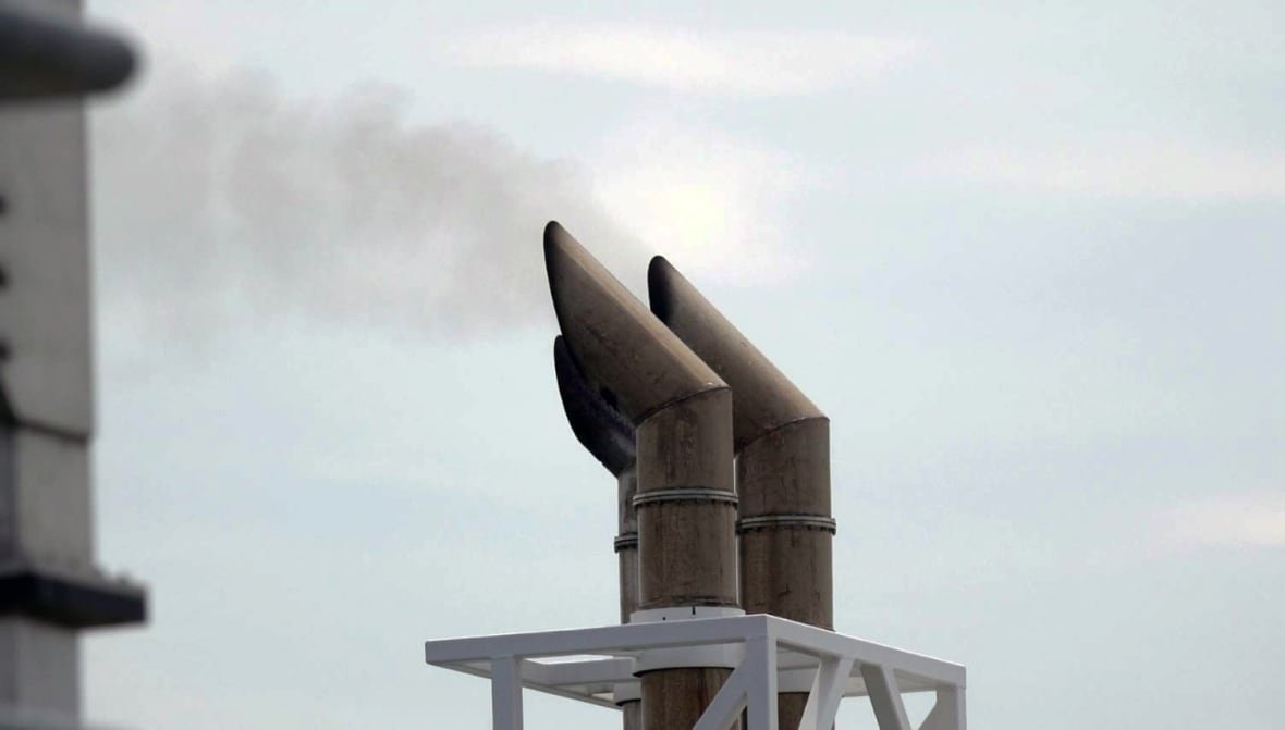 A cloud of grey smoke can be seen coming out of three pipes.