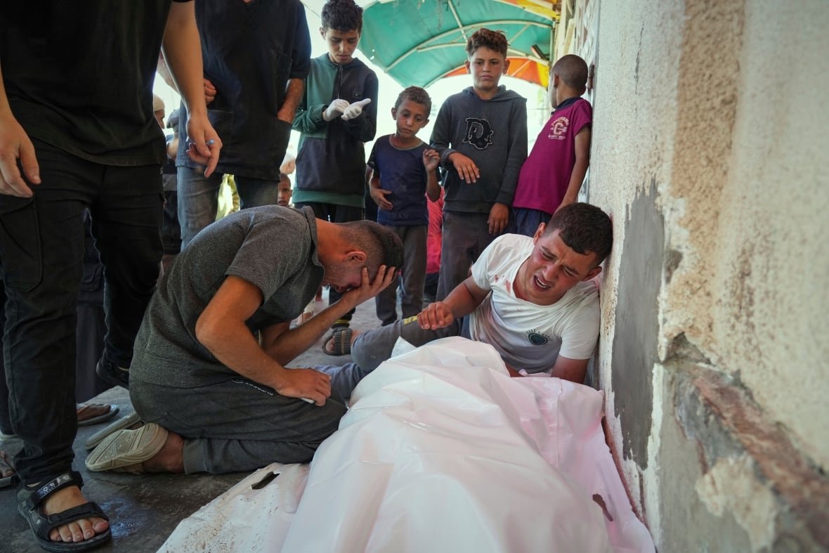 Relatives mourn over the bodies of loved ones wrapped in white shroud.