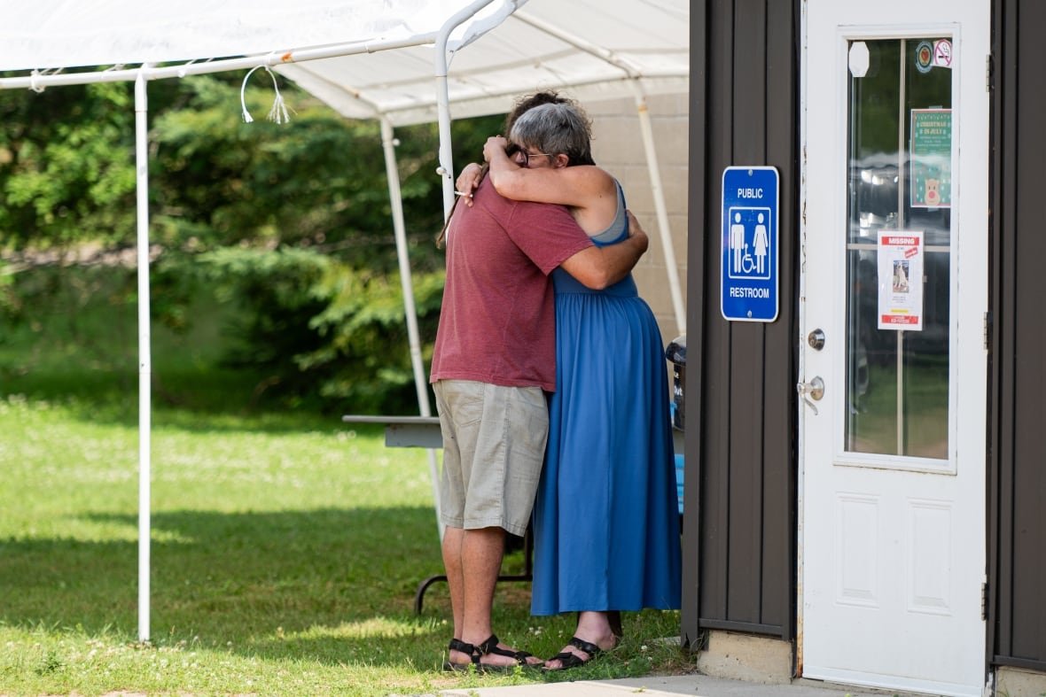 A pair of local area residents hug before the town hall meeting.