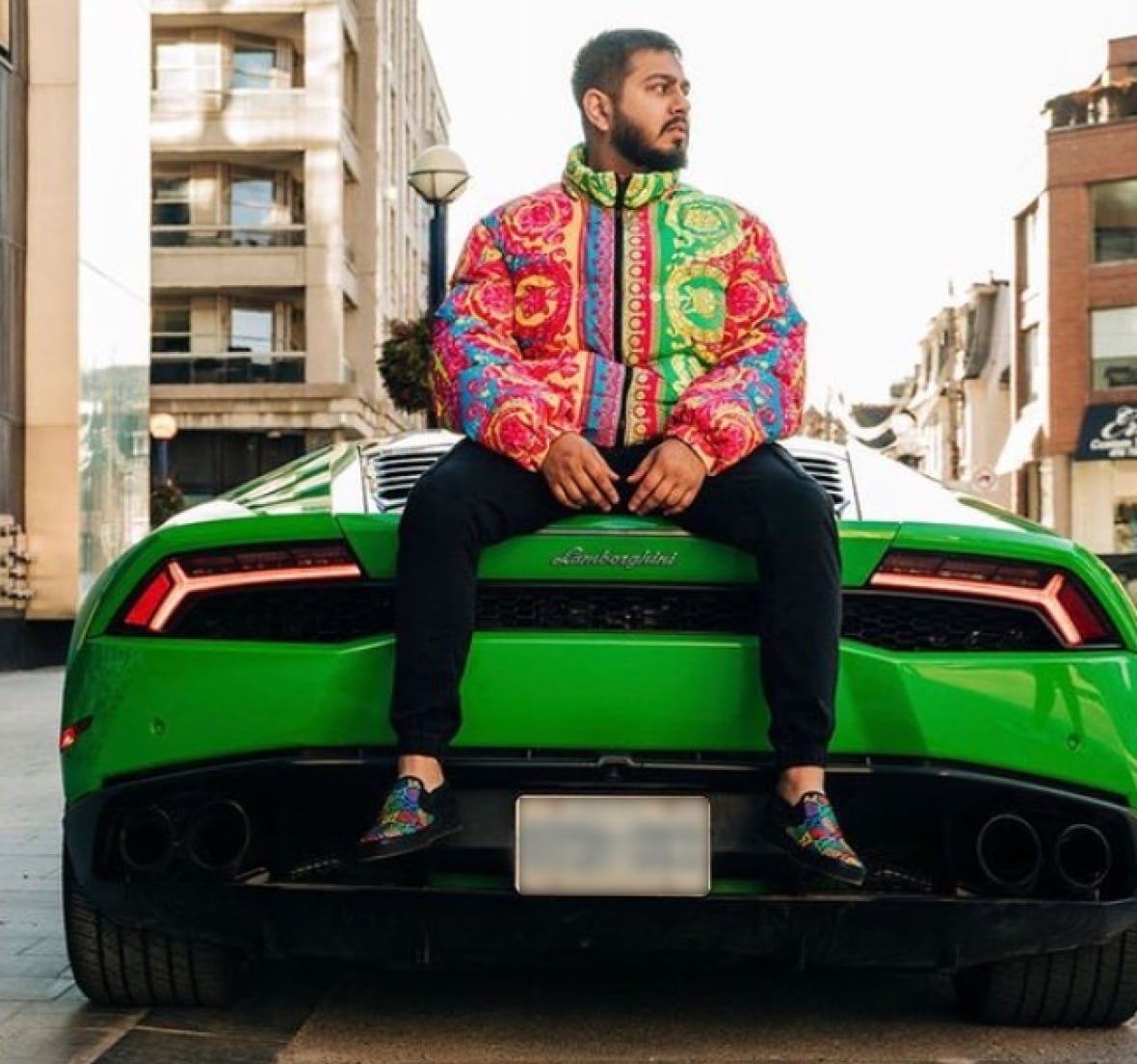 Man sitting on the back of a green Lamborghini.