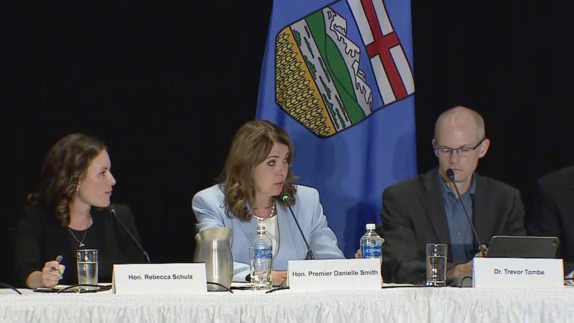 A seated woman speaks, flanked by a man and another woman.