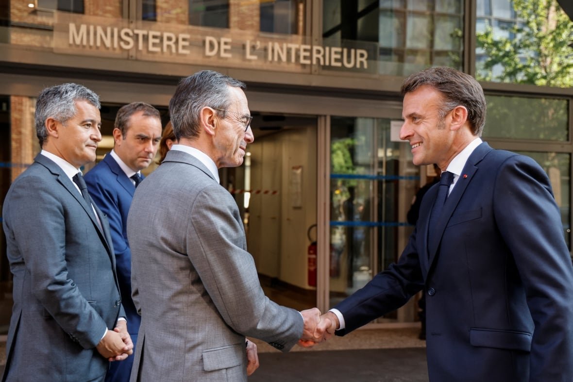 Two men in suits shake hands. 