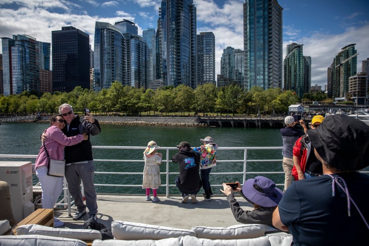 People pose for photos by an inlet near buildings