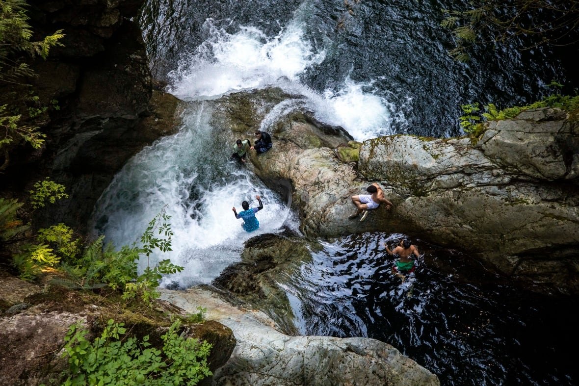 Teenagers jump into the water at Lynn Canyon Park.