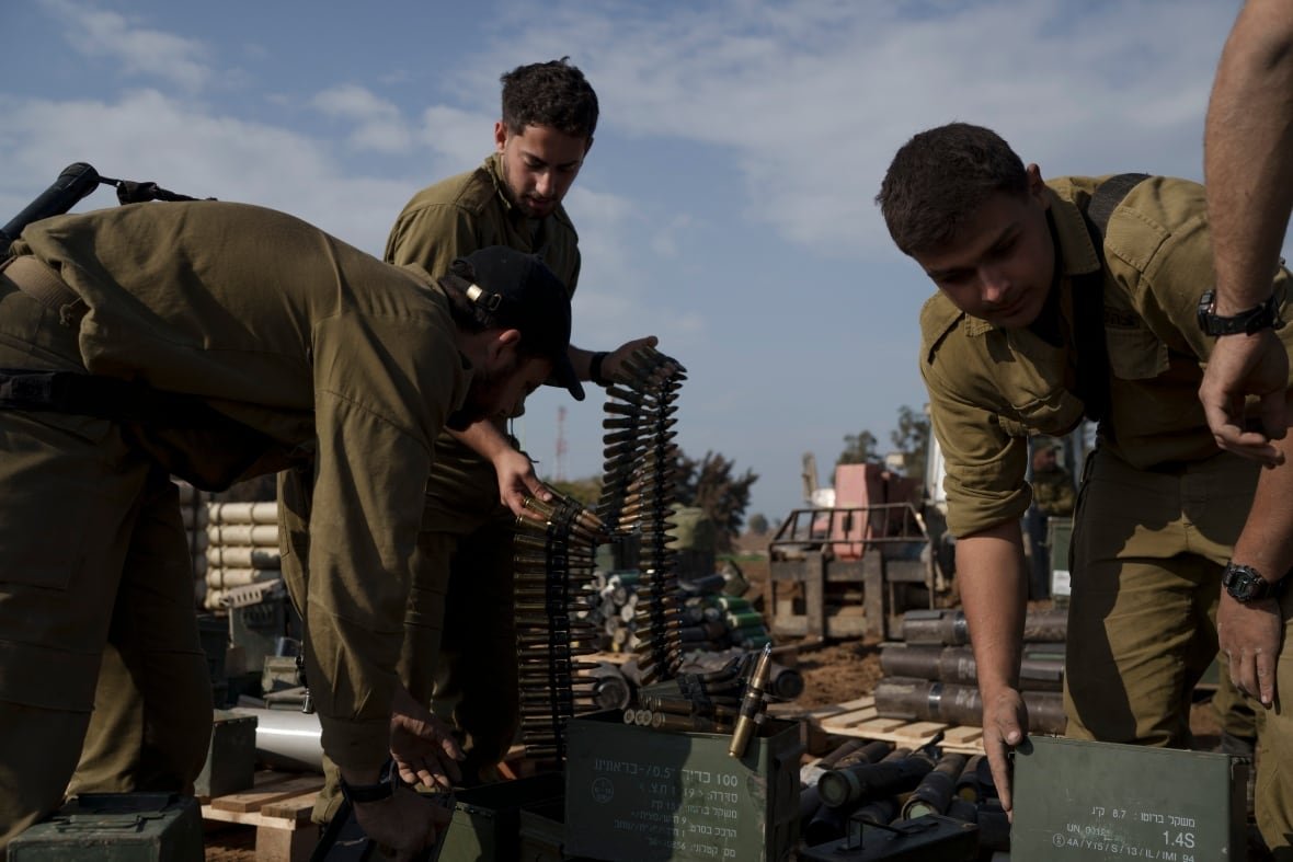 Three soliders sort belts of ammunition in boxes.