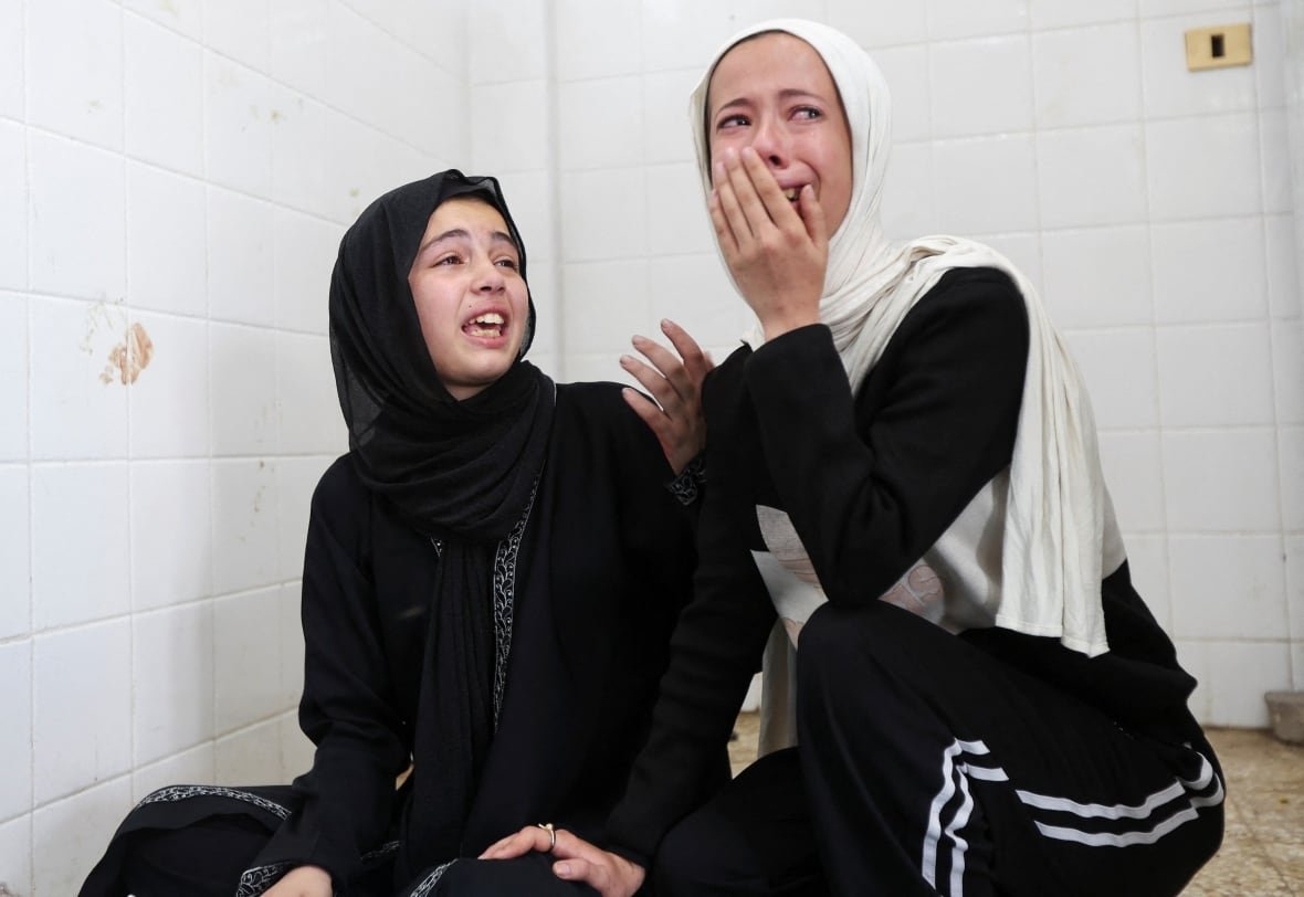 Young women weep at a hospital.