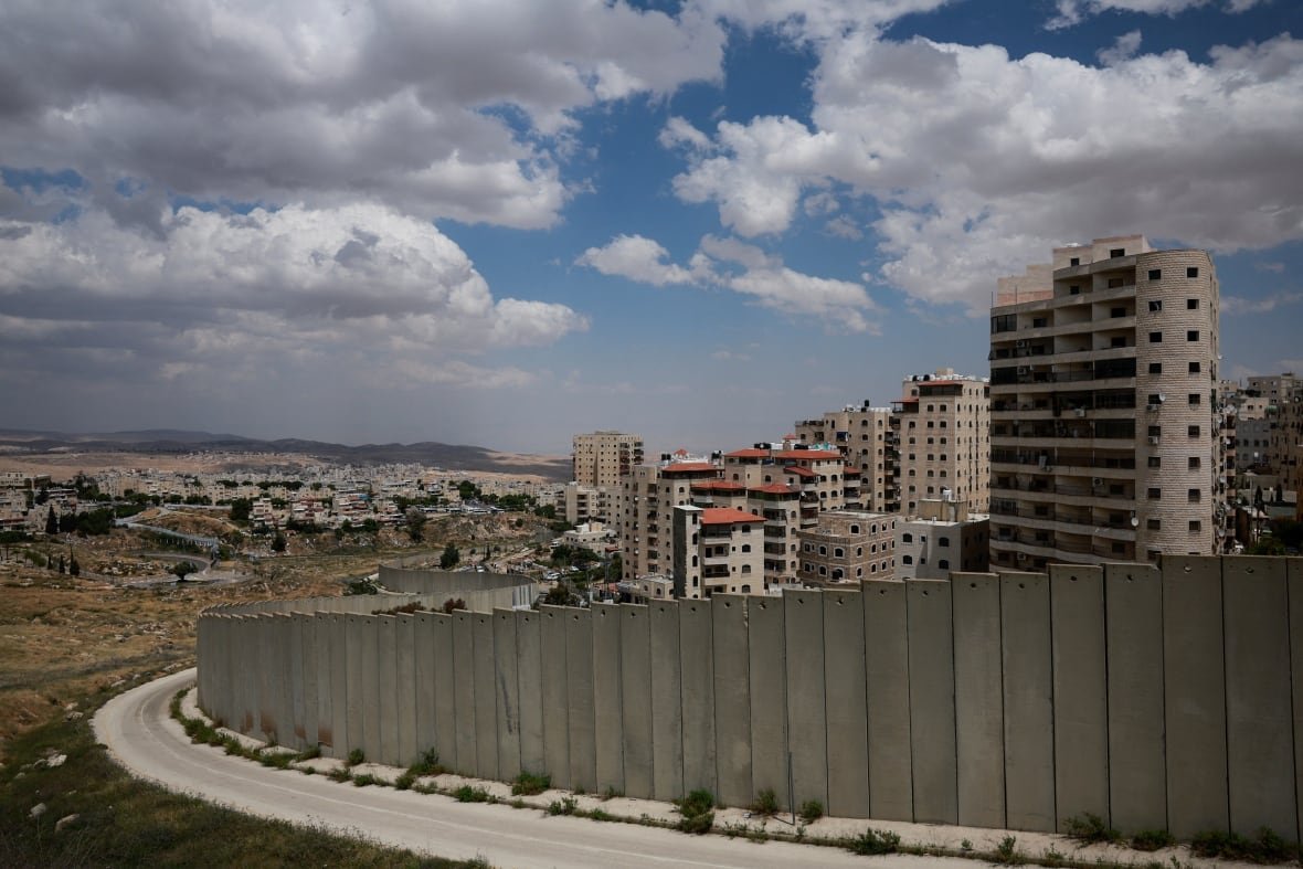 A wall barrier winds around the outskirts of a refugee camp.