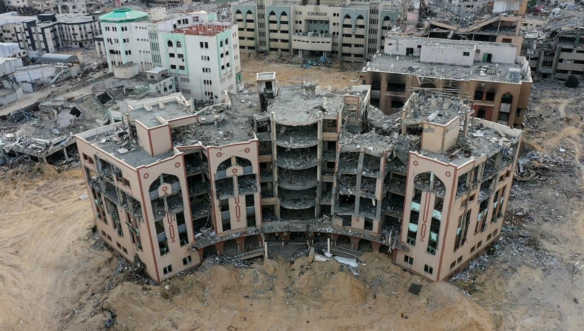 A building stands ruined in the midst of war. 