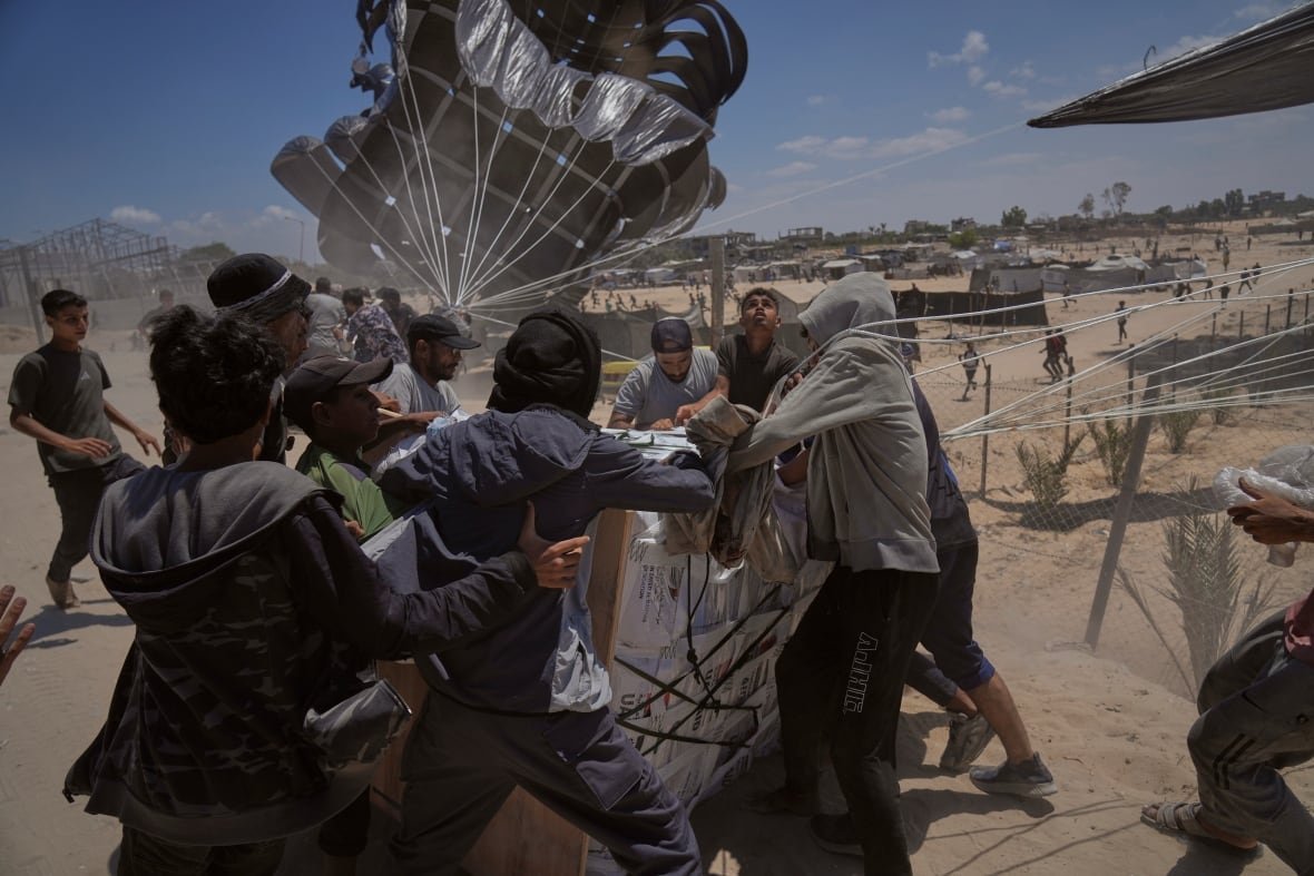 Palestinians rush to collect humanitarian aid airdropped by parachutes.