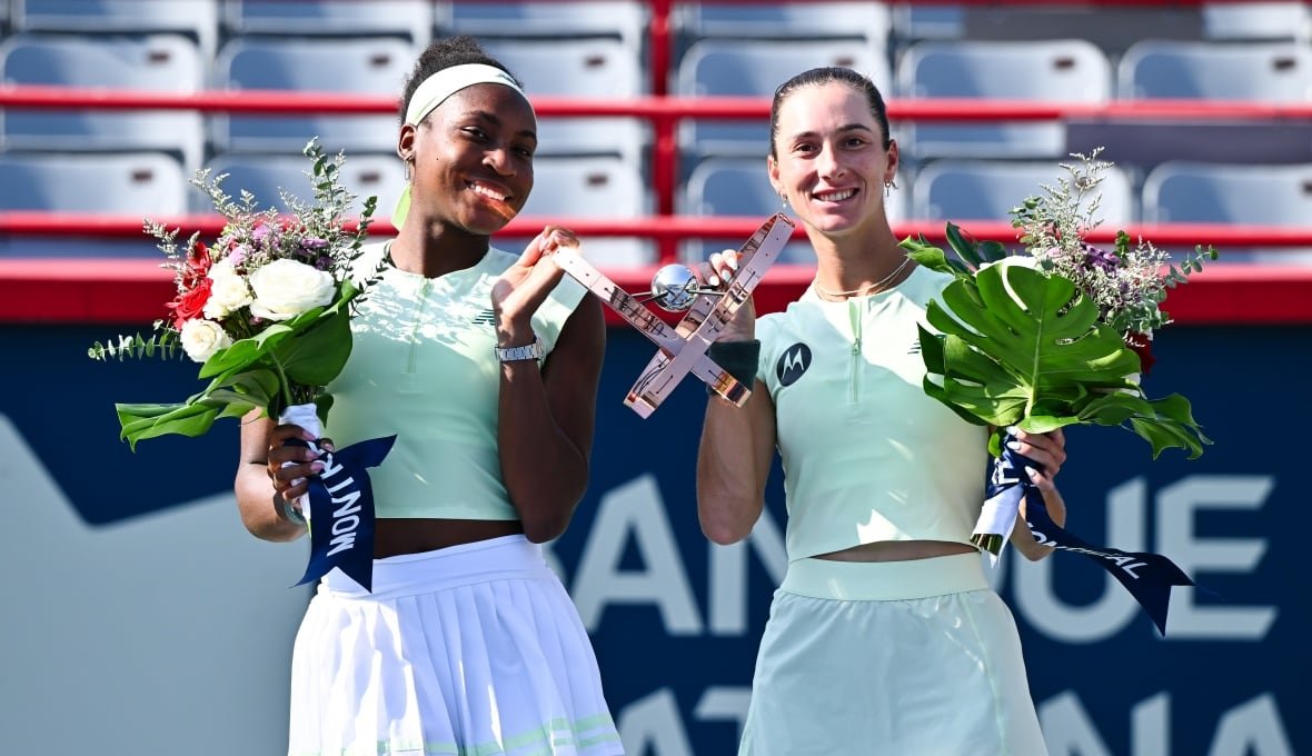A women's doubles team poses with a trophy after winning a tournament.