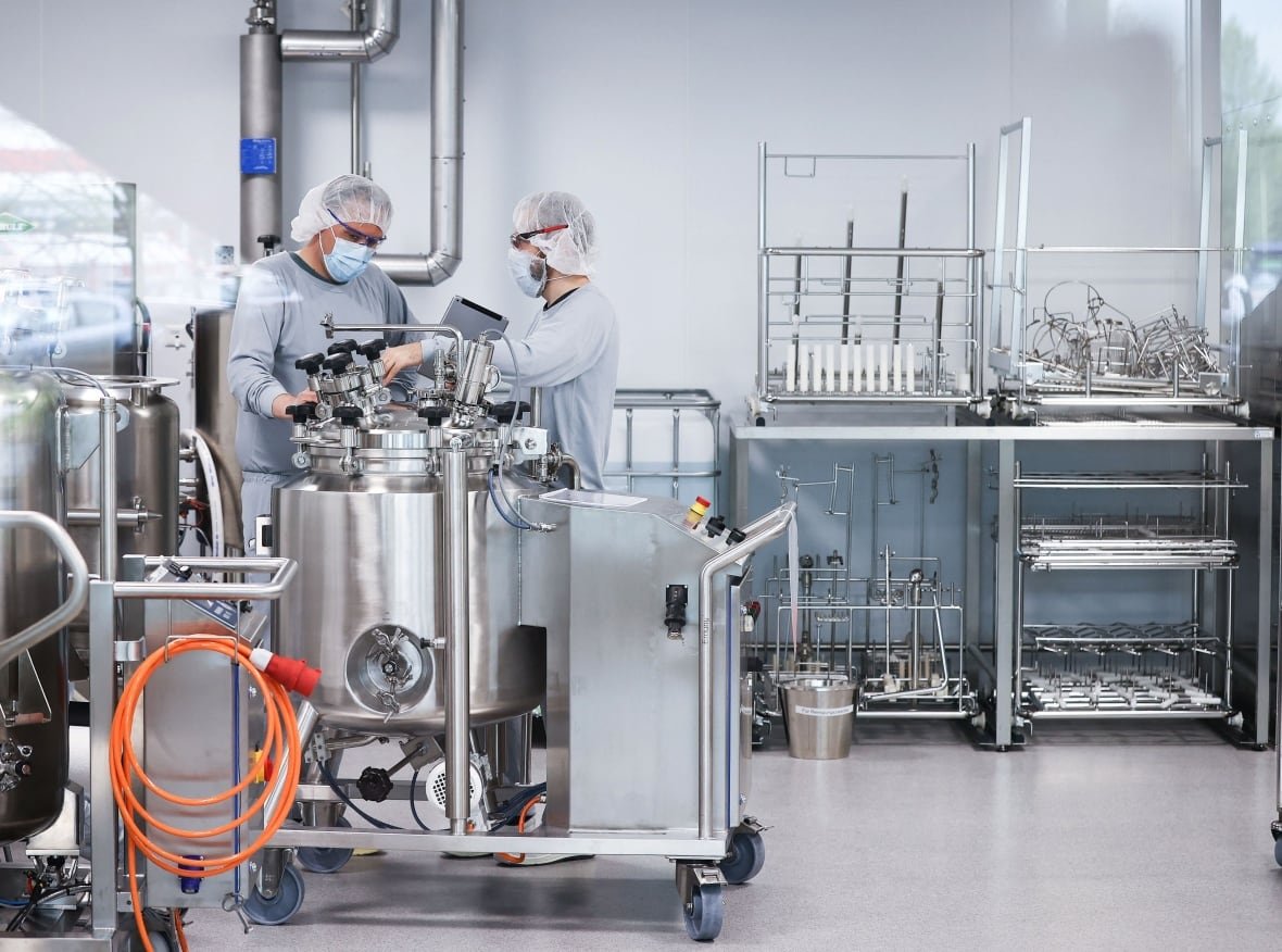 Employees in clean room clothes work on the production of Pfizer/BioNTech's Comirnaty COVID-19 vaccine near Hamburg, Germany, on April 30, 2021, amid the coronavirus pandemic. 