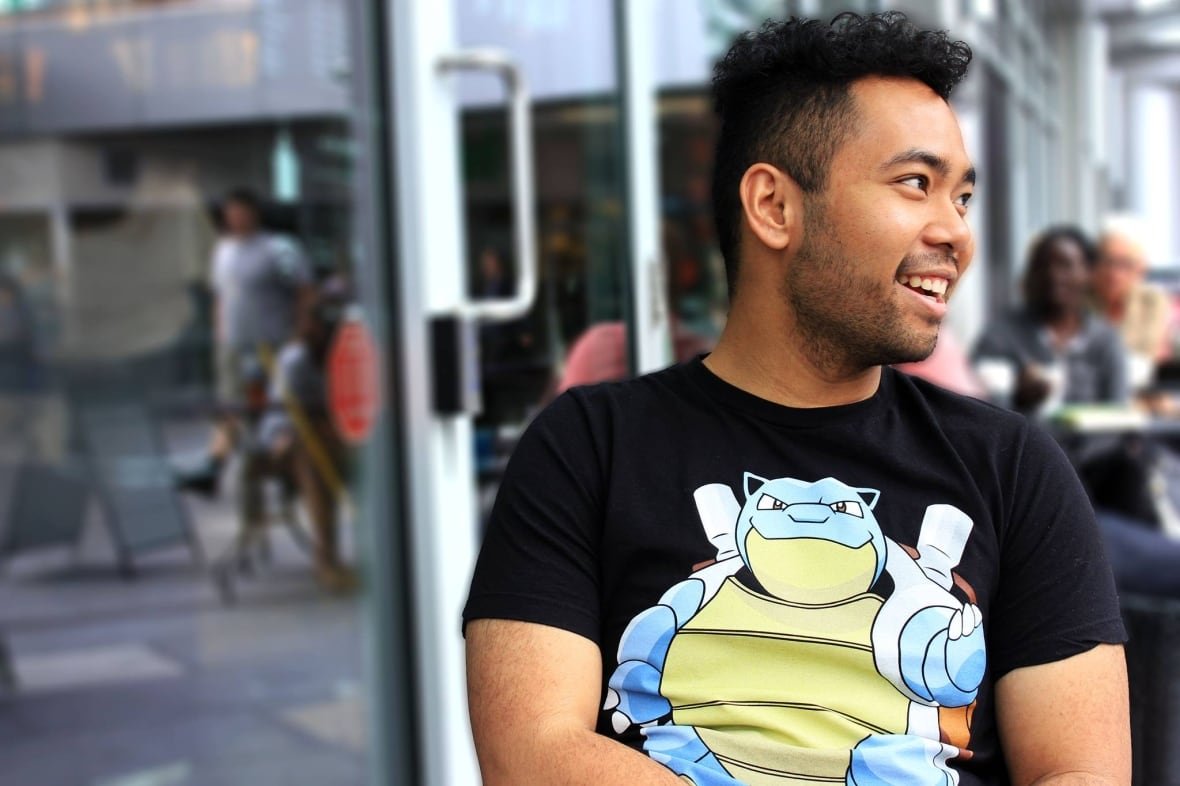 A man smiling and looking to the side wearing a Pokemon t-shirt.