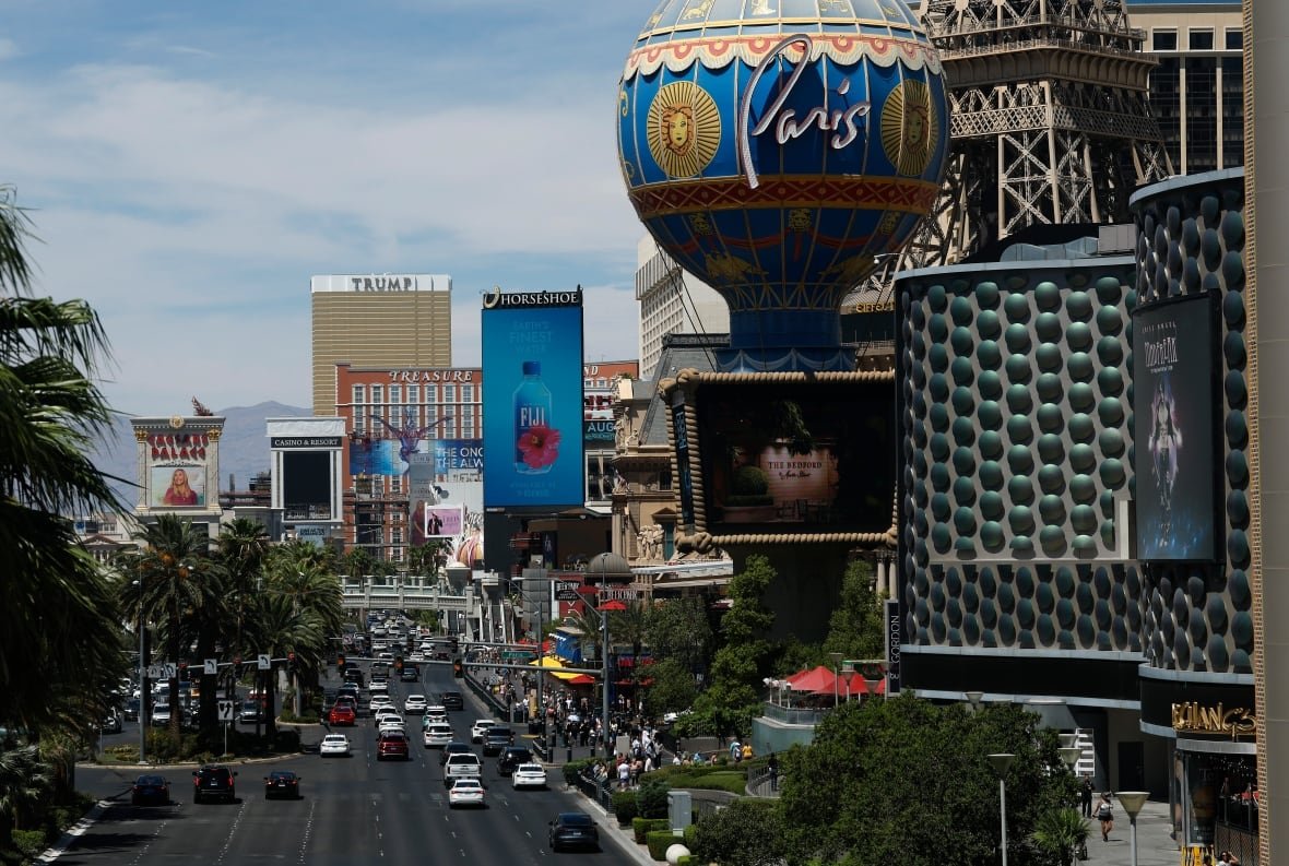 A view of the Las Vegas Strip, with vehicles on the road adjacent to hotels and buildings.