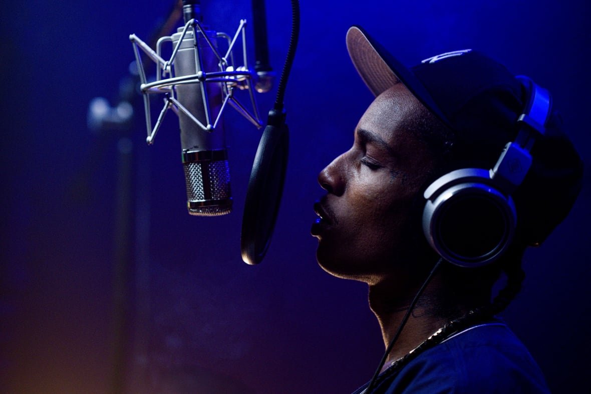 A man sings into a studio microphone. 