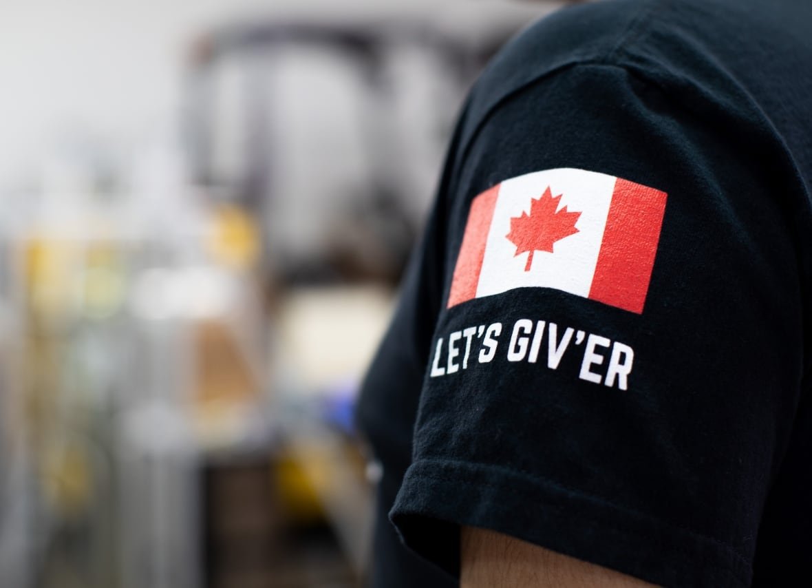 The sleeve of a black t-shirt is shown with a patch that reads, "Let's Giv'er."