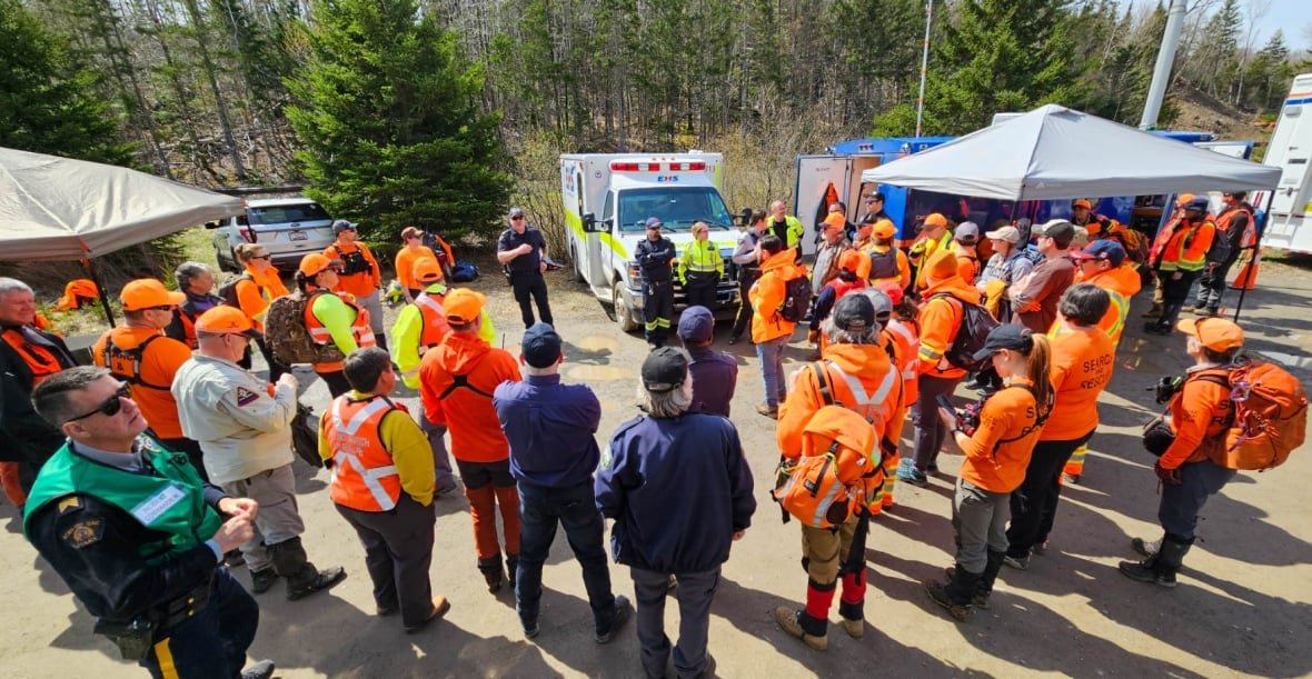 A group of people in bright orange are gathered outside.