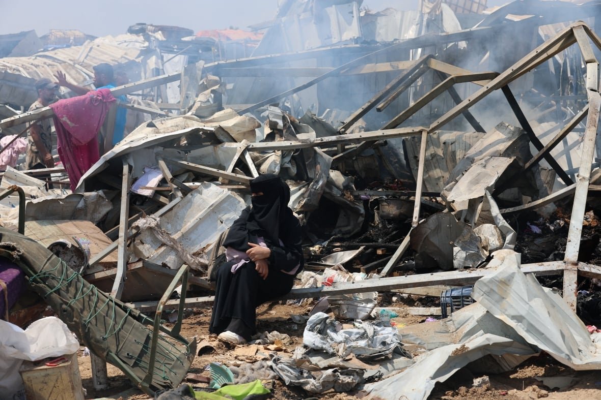 A woman sits in wreckage.
