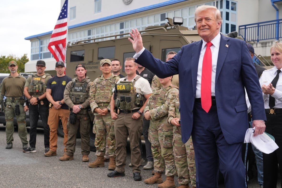 A person waves while standing in front of a line of soldiers.