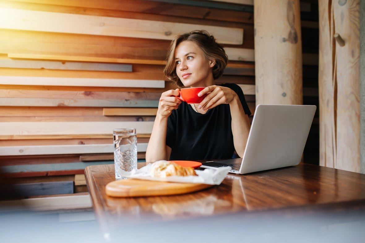 A young woman sitting at a table drinking coffee.