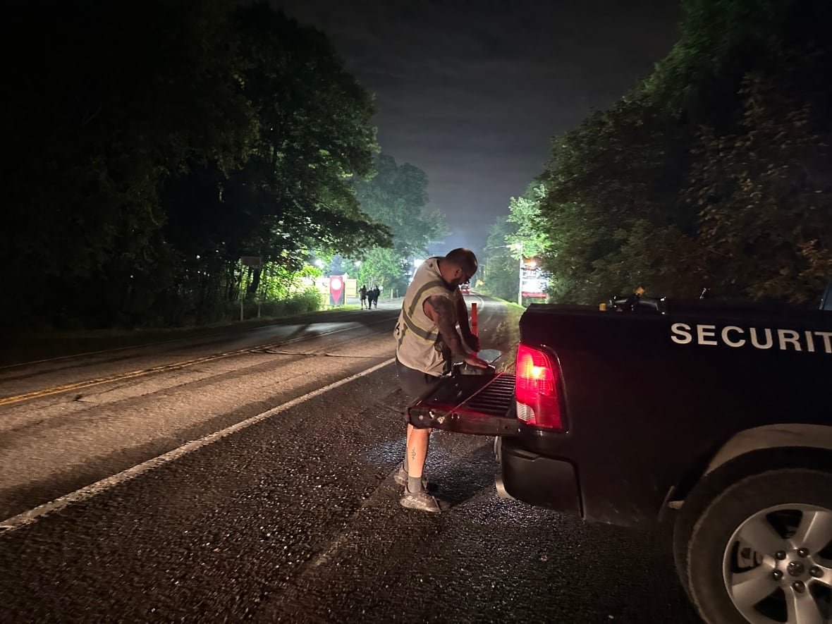 A man wearing a reflective vest is putting pilons into the back of a pickup truck.