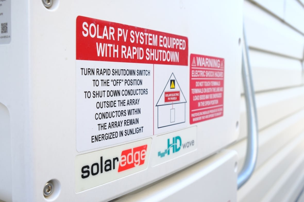 A close-up image of warning labels on a solar power sytem attached to the side of a home. 