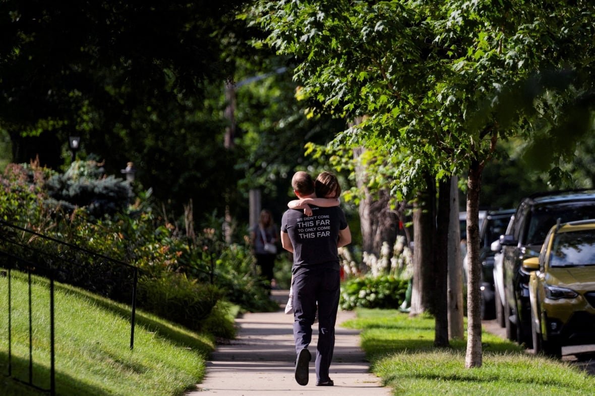 A man is seen walking away with a child in his arms