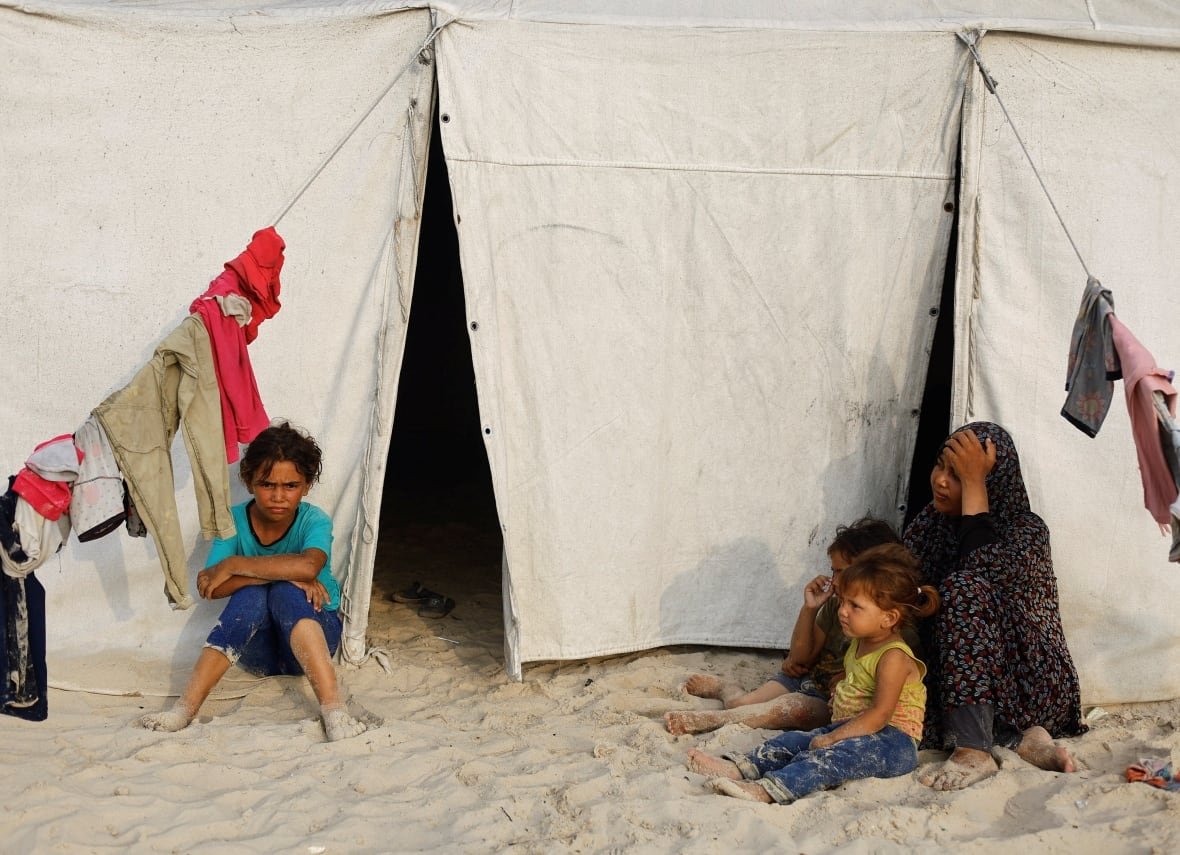 Palestinians, displaced by the Israeli offensive, rest outside their tent.