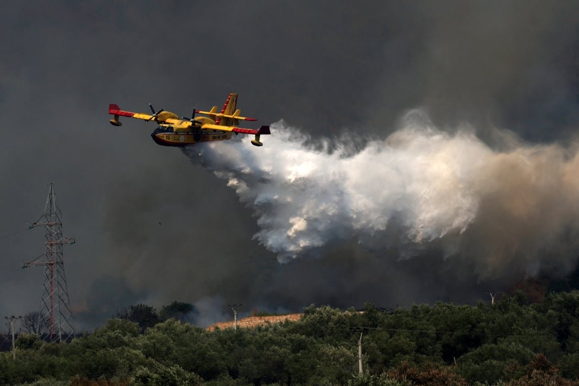 A firefighting aircraft is seen flying in Delvina, Albania, amid an ongoing wildfire in August 2025.