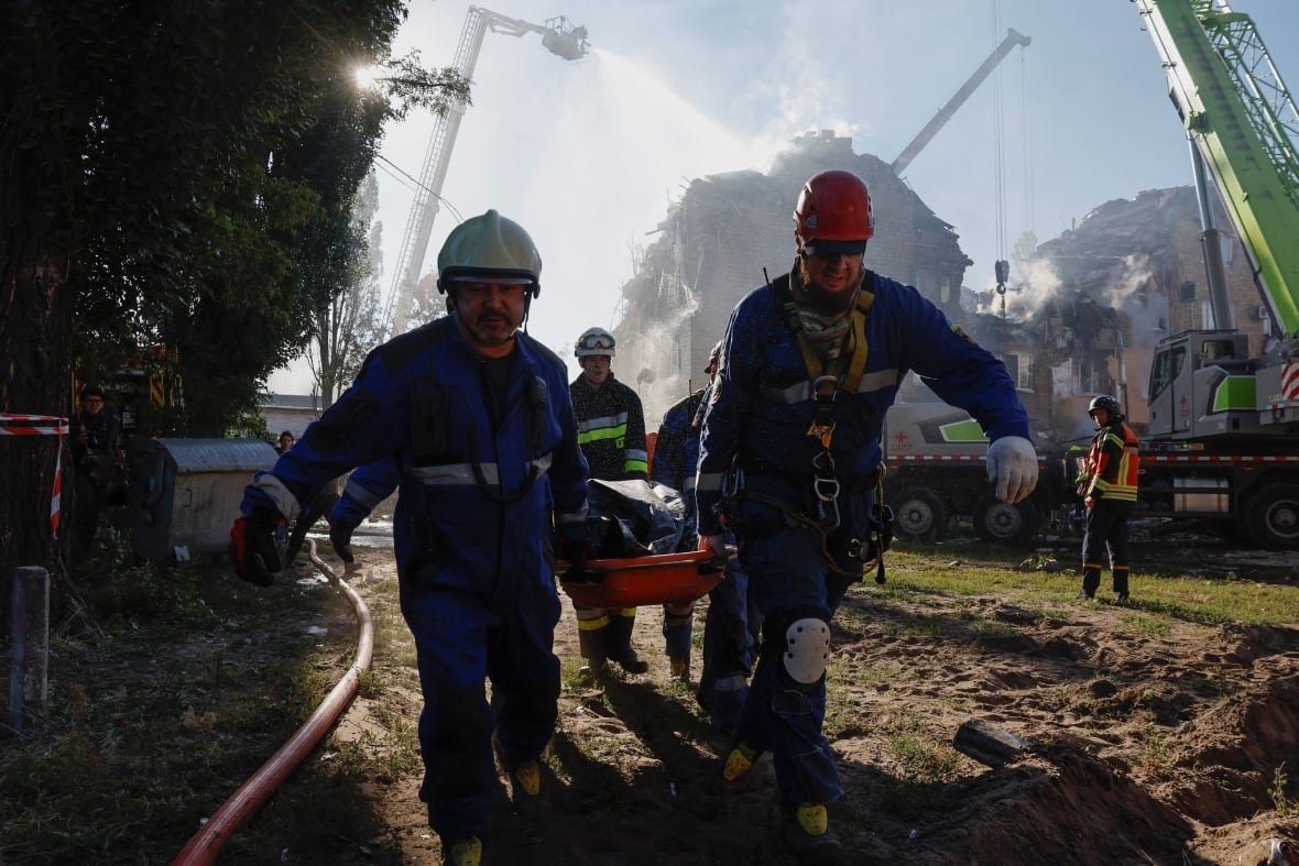 First responders carry a stretcher out of a damaged area.