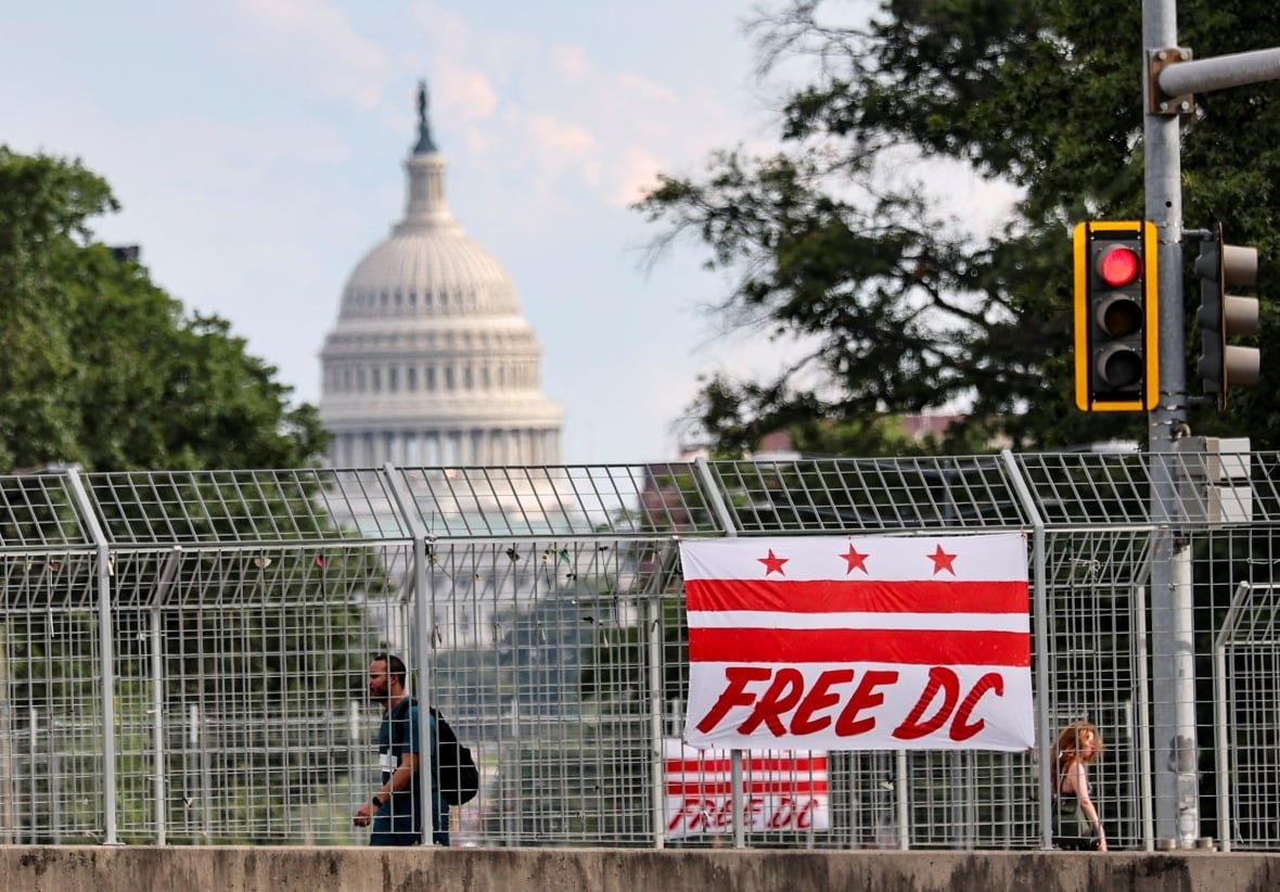 A banner depicting the Washington, D.C., flag with a text reading "Free DC" hangs from an overpass in the U.S. capital city.