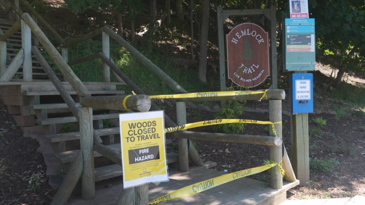 Entrance to a trail with yellow tape across it and sign saying "trail closed to travel, fire hazard."