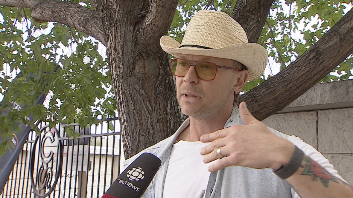 A man wears a cowboy had and sunglasses.