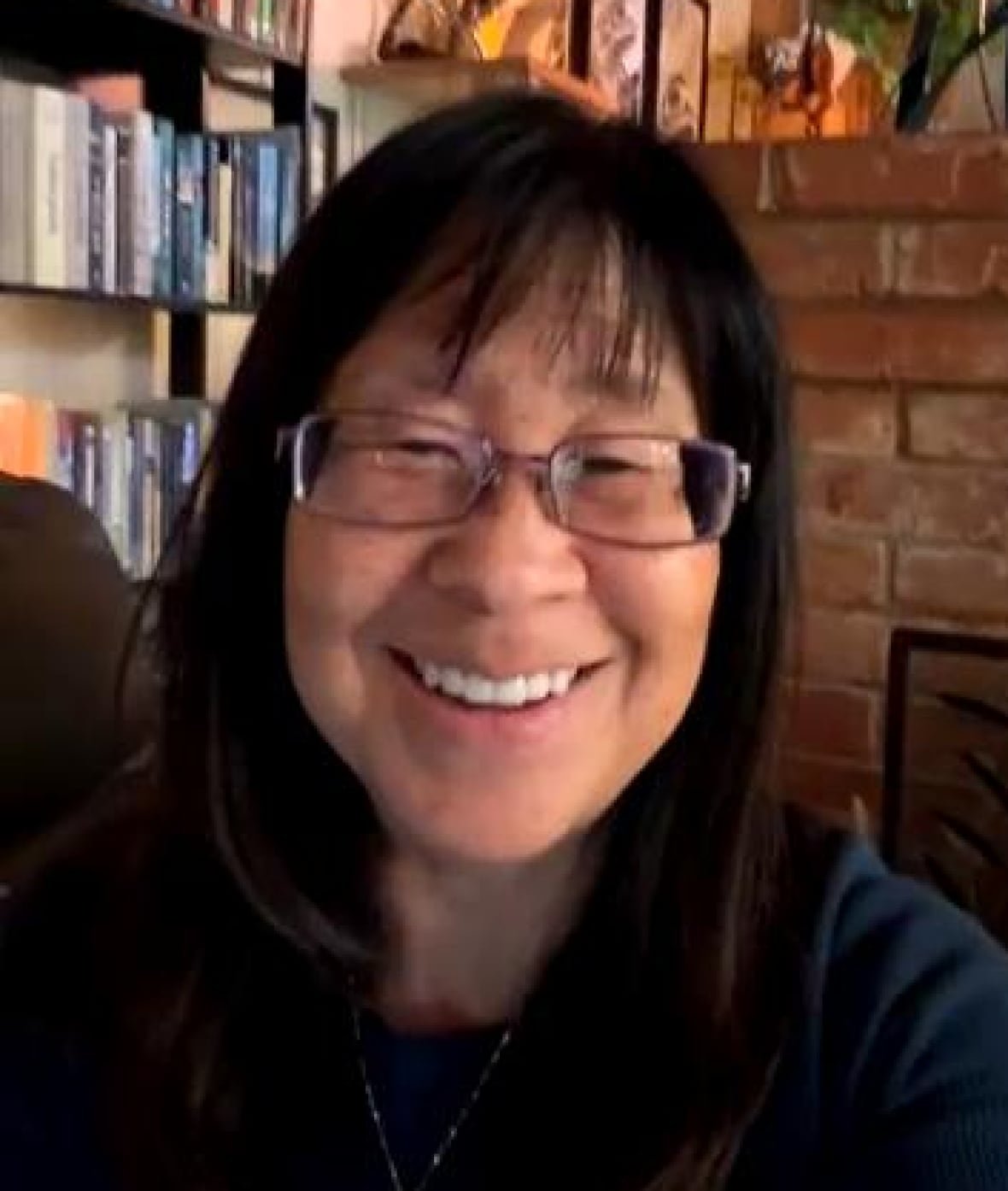 A woman sits in a room with a wood paneling on the ceiling.